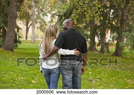 Stock Photograph - Interracial Married Couple Walking In A Park In Autumn; Edmonton Alberta Canada. Fotosearch