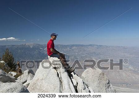 Male Hiker Sitting On Top Of Mountain Peak Over Looking A Desert Valley With Blue Sky; Palm Springs California United States Of America View Large Photo Image Stock Photo - Male Hiker Sitting On Top Of Mountain Peak Over Looking A Desert Valley With Blue Sky; Palm Springs California United States Of America. Fotosearch