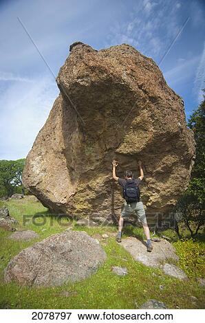 Man with backpack pushing against large boulder; sutter buttes california united states of america View Large Photo Image Stock Photo - Man with backpack pushing against large boulder; sutter buttes california united states of america. Fotosearch