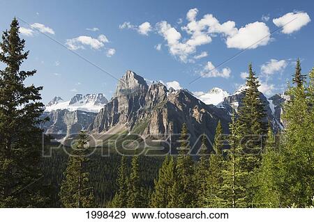 Mountain Vista With Cliff Face And Blue Sky And Clouds; Alberta Canada View Large Photo Image Stock Photo - Mountain Vista With Cliff Face And Blue Sky And Clouds; Alberta Canada. Fotosearch