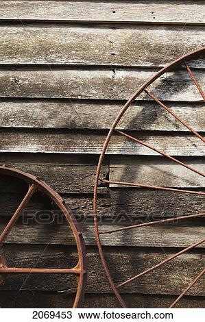 Stock Image - Old Wagon Wheels Against A Wooden Wall; Margaret River West Australia Australia. Fotosearch