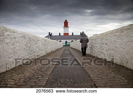 Person walking on a paved walkway towards a lighthouse; south shields tyne and wear england View Large Photo Image Stock Image - Person walking on a paved walkway towards a lighthouse; south shields tyne and wear england. Fotosearch