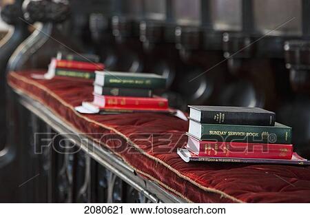 Stock Image - Piles of hymn and service books on a bench in a church; staindrop durham england. Fotosearch