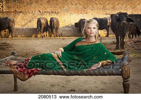 Portrait of a blond woman wearing a sari and laying on a hammock with cattle in the background; ludhiana punjab india View Large Photo Image Stock Image - Portrait of a blond woman wearing a sari and laying on a hammock with cattle in the background; ludhiana punjab india. Fotosearch