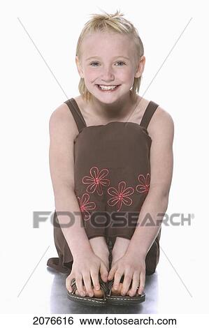 Portrait of a girl with blond hair wearing a brown tank dress sitting on the floor touching toes; troutdale oregon united states of america View Large Photo Image Stock Photograph - Portrait of a girl with blond hair wearing a brown tank dress sitting on the floor touching toes; troutdale oregon united states of america. Fotosearch