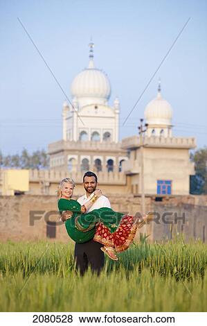 Portrait of a mixed race couple her wearing a sari with a temple in the background; ludhiana punjab india View Large Photo Image Stock Photo - Portrait of a mixed race couple her wearing a sari with a temple in the background; ludhiana punjab india. Fotosearch