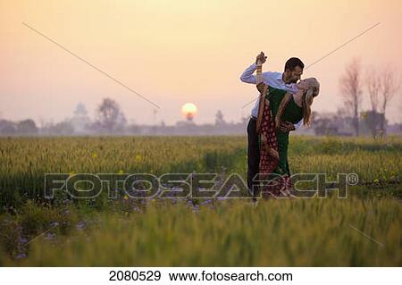 Portrait of a mixed race couple her wearing a sari in a field at sunset; ludhiana punjab india View Large Photo Image Stock Photo - Portrait of a mixed race couple her wearing a sari in a field at sunset; ludhiana punjab india. Fotosearch