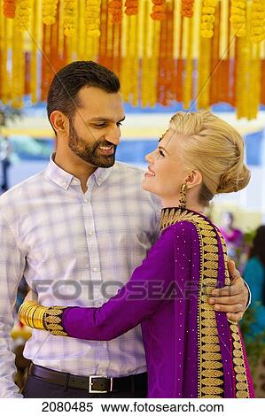 Stock Photography - Portrait of a mixed race couple in an embrace with her wearing a sari; ludhiana punjab india. Fotosearch