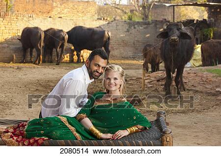 Picture - Portrait of a mixed race couple with her wearing a sari and cattle in the background; ludhiana punjab india. Fotosearch