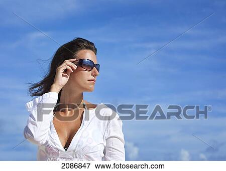 Portrait of a woman wearing sunglasses against a blue sky; punta cana la altagracia dominican republic View Large Photo Image Stock Photo - Portrait of a woman wearing sunglasses against a blue sky; punta cana la altagracia dominican republic. Fotosearch