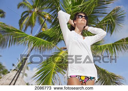 Portrait of a woman with a white swimsuit cover up and sunglasses with a palm tree in the background; punta cana la altagracia dominican republic View Large Photo Image Stock Image - Portrait of a woman with a white swimsuit cover up and sunglasses with a palm tree in the background; punta cana la altagracia dominican republic. Fotosearch