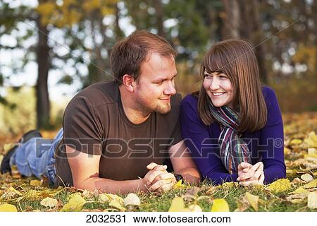 Stock Image - Portrait Of A Young Couple Laying In The Leaves In Autumn; Edmonton Alberta Canada. Fotosearch