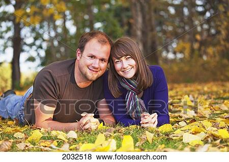 Portrait Of A Young Couple Laying In The Leaves In Autumn; Edmonton Alberta Canada View Large Photo Image Stock Photo - Portrait Of A Young Couple Laying In The Leaves In Autumn; Edmonton Alberta Canada. Fotosearch