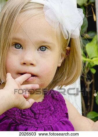 Stock Image - Portrait Of A Young Girl With Down Syndrome With Her Finger In Her Mouth; Three Hills Alberta Canada. Fotosearch