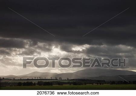 Rays of sunlight shining on the hills through dark storm clouds; northumberland england View Large Photo Image Stock Photograph - Rays of sunlight shining on the hills through dark storm clouds; northumberland england. Fotosearch
