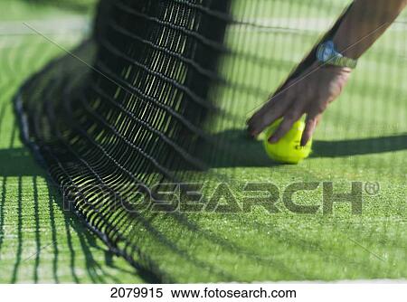 Stock Photography - Retrieving a tennis ball by the net; tarifa cadiz andalusia spain. Fotosearch