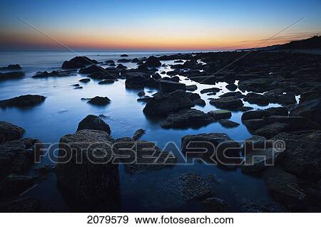 Rocks in the tranquil water along the coast at sunset; tarifa cadiz andalusia spain View Large Photo Image Stock Photo - Rocks in the tranquil water along the coast at sunset; tarifa cadiz andalusia spain. Fotosearch