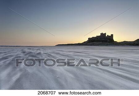 Sand Blowing Across The Beach With Bamburgh Castle In The Distance At Sunset; Bamburgh Northumberland England View Large Photo Image Stock Photo - Sand Blowing Across The Beach With Bamburgh Castle In The Distance At Sunset; Bamburgh Northumberland England. Fotosearch