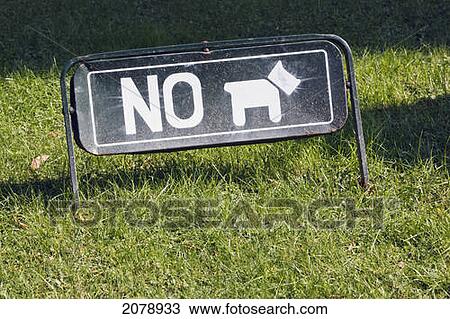 Stock Image - Sign saying 'no dogs' with a word and a pictograph on grass outside el prado museum; madrid spain. Fotosearch