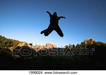Silhouette Of A Person Jumping In The Air Against A Blue Sky; Black Hills South Dakota United States Of America View Large Photo Image Picture - Silhouette Of A Person Jumping In The Air Against A Blue Sky; Black Hills South Dakota United States Of America. Fotosearch
