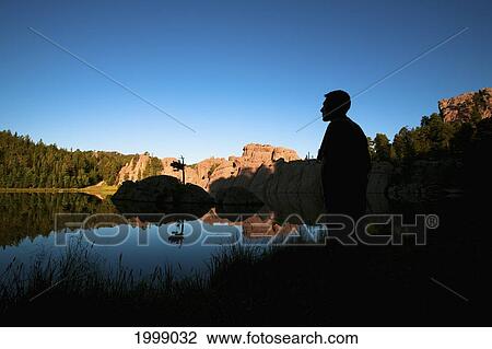 Silhouette Of A Young Man Standing At The Water's Edge Of Sylvan Lake; Black Hills South Dakota United States Of America View Large Photo Image Stock Image - Silhouette Of A Young Man Standing At The Water's Edge Of Sylvan Lake; Black Hills South Dakota United States Of America. Fotosearch