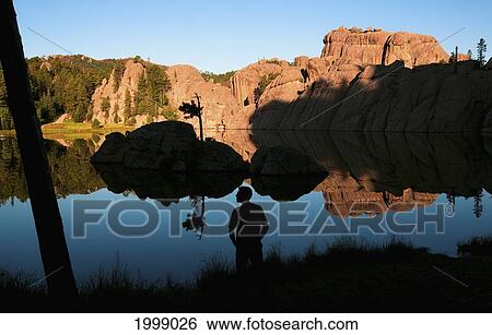 Silhouette Of A Young Man Standing At The Water's Edge Of Sylvan Lake; Black Hills South Dakota United States Of America View Large Photo Image Stock Photograph - Silhouette Of A Young Man Standing At The Water's Edge Of Sylvan Lake; Black Hills South Dakota United States Of America. Fotosearch