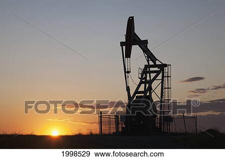 Silhouette Of Pump Jack With The Orange Glow Of The Sun Rising On The Horizon; Longview Alberta Canada View Large Photo Image Stock Photo - Silhouette Of Pump Jack With The Orange Glow Of The Sun Rising On The Horizon; Longview Alberta Canada. Fotosearch