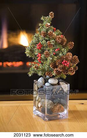 Small Real Fur Tree Decorated With Cones And Red Berries (Christmas Tree) On A Table In Glass Vase Filled With Round Stones And A Glowing Firplace In The Background; Calgary Alberta Canada View Large Photo Image Stock Image - Small Real Fur Tree Decorated With Cones And Red Berries (Christmas Tree) On A Table In Glass Vase Filled With Round Stones And A Glowing Firplace In The Background; Calgary Alberta Canada. Fotosearch