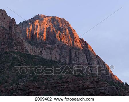 Stock Image - Sunlight On The Top Of A Sandstone Cliff In Zion National Park; Utah United States Of America. Fotosearch
