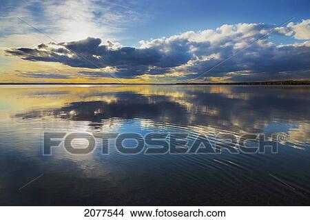Sunrise and clouds reflected into a lake; pigeon lake alberta canada View Large Photo Image Picture - Sunrise and clouds reflected into a lake; pigeon lake alberta canada. Fotosearch