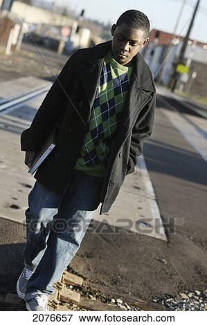 Teenage boy holding a school book and walking on train tracks; portland oregon united states of america View Large Photo Image Stock Photo - Teenage boy holding a school book and walking on train tracks; portland oregon united states of america. Fotosearch
