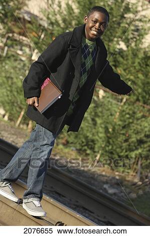 Teenage boy holding a school book and walking on railroad tracks; portland oregon united states of america View Large Photo Image Stock Photography - Teenage boy holding a school book and walking on railroad tracks; portland oregon united states of america. Fotosearch