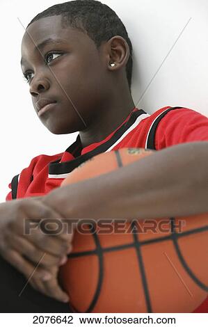 Stock Image - Teenage boy in red jersey holding basketball; portland oregon united states of america. Fotosearch