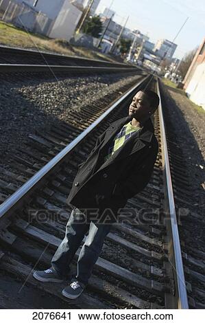 Teenage boy standing on railroad tracks; portland oregon united states of america View Large Photo Image Stock Image - Teenage boy standing on railroad tracks; portland oregon united states of america. Fotosearch