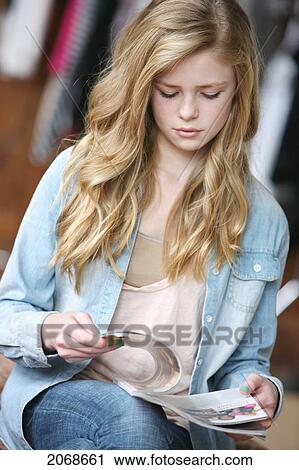 Stock Image - Teenage Girl With Long Blond Hair And Blue Eyes Reading A Magazine; Troutdale Oregon United States Of America. Fotosearch