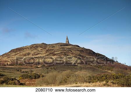 The peak of a structure as seen against a blue sky at the top of a hill; dumfries scotland View Large Photo Image Stock Image - The peak of a structure as seen against a blue sky at the top of a hill; dumfries scotland. Fotosearch