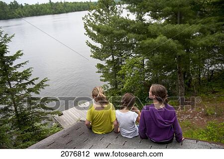 Three girls sitting on the edge of a roof by a lake; lake of the woods ontario canada View Large Photo Image Stock Image - Three girls sitting on the edge of a roof by a lake; lake of the woods ontario canada. Fotosearch