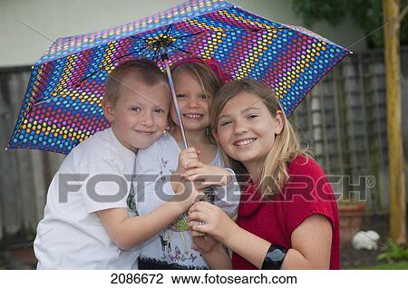 Three siblings under an umbrella; moraga california united states of america View Large Photo Image Stock Image - Three siblings under an umbrella; moraga california united states of america. Fotosearch