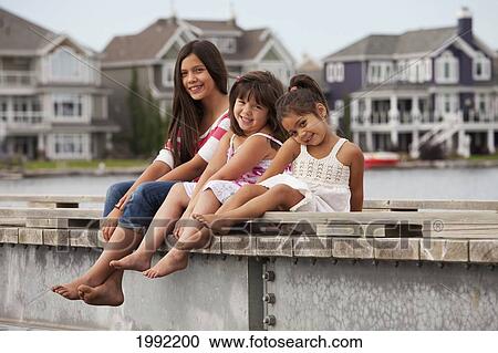 Stock Image - Three Sisters On A Pier At A Residential Lake Community; Edmonton Alberta Canada. Fotosearch