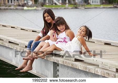 Stock Image - Three Sisters On A Pier At A Residential Lake Community; Edmonton Alberta Canada. Fotosearch