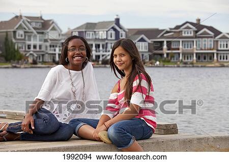 Picture - Two Adolescent Friends Spending Time Together At A Residential Lake; Edmonton Alberta Canada. Fotosearch