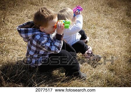 Two children looking through plastic binoculars; spruce grove alberta canada View Large Photo Image Stock Photo - Two children looking through plastic binoculars; spruce grove alberta canada. Fotosearch