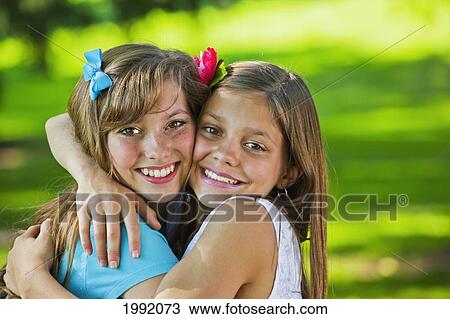 Stock Image - Two Sisters Hugging In A Park; Edmonton Alberta Canada. Fotosearch