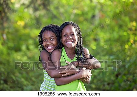 Stock Photograph - Two Sisters Hugging In A Park; Edmonton Alberta Canada. Fotosearch