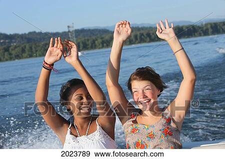 Two Teenage Girls Sitting In The Back Of A Boat With Arms Raised; Troutdale Oregon United States Of America View Large Photo Image Stock Photo - Two Teenage Girls Sitting In The Back Of A Boat With Arms Raised; Troutdale Oregon United States Of America. Fotosearch