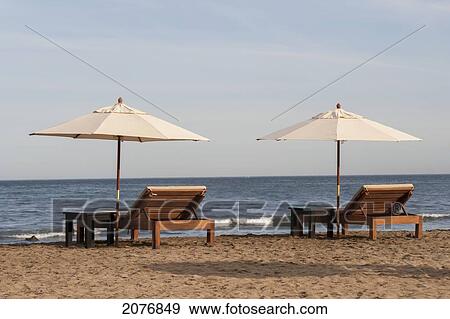 Two wooden lounge chairs and white umbrellas on the beach; sayulita mexico View Large Photo Image Stock Photo - Two wooden lounge chairs and white umbrellas on the beach; sayulita mexico. Fotosearch