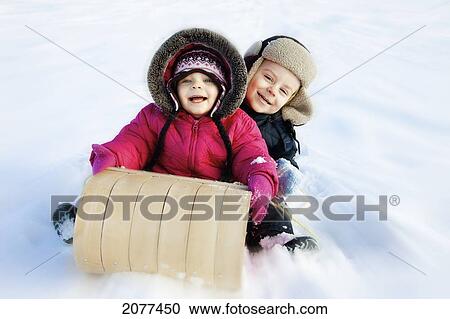 Two young children on a toboggan in the snow; spruce grove alberta canada View Large Photo Image Stock Image - Two young children on a toboggan in the snow; spruce grove alberta canada. Fotosearch