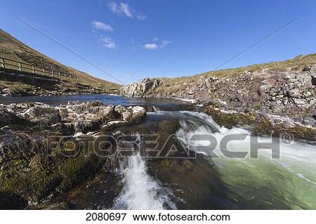 Stock Photo - Water flowing over rocks in a river through the cheviot hills; cheviots northumberland england. Fotosearch