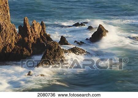 Stock Photograph - Waves breaking on the arrecife de las sirenas or mermaid's reef in cabo de gata-nijar natural park; almeria province spain. Fotosearch