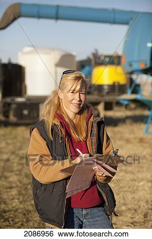 Woman documenting notes with farm equipment in the background; three hills alberta canada View Large Photo Image Stock Photograph - Woman documenting notes with farm equipment in the background; three hills alberta canada. Fotosearch